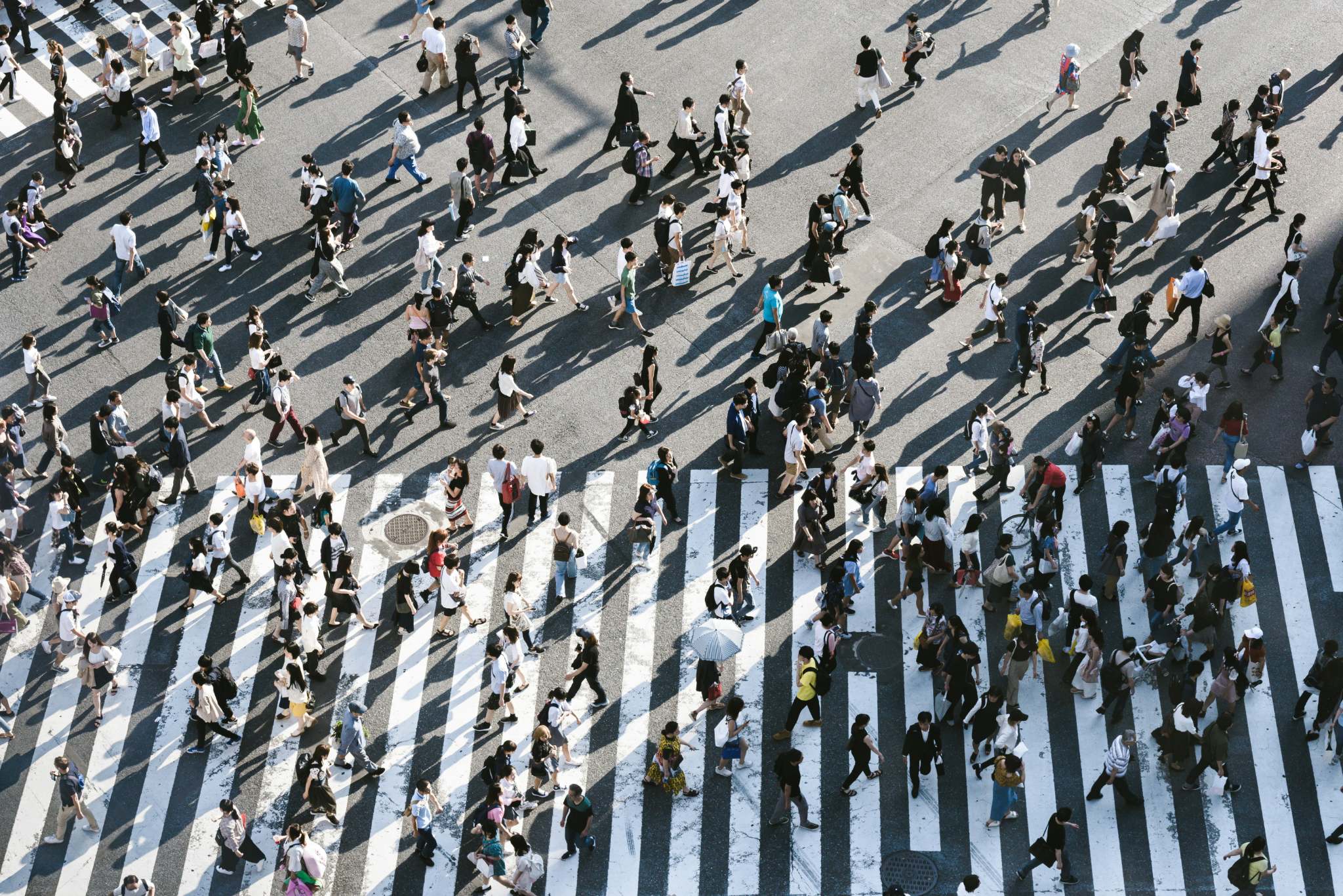 Centenas de pessoas caminhando sobre uma faixa de pedestres